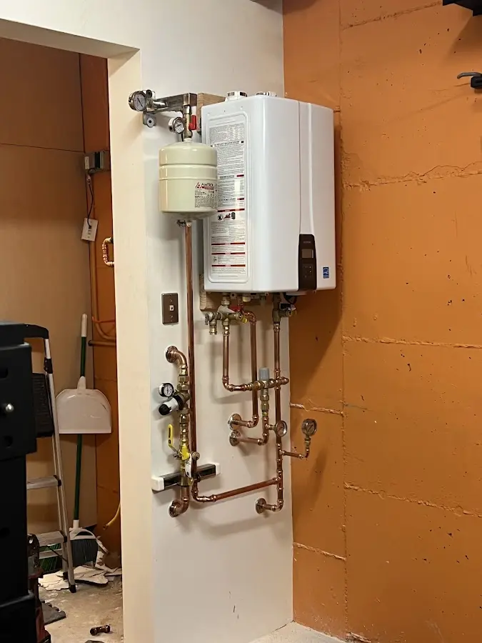 Plumbing technician inspecting water heater connections in Sudbury
